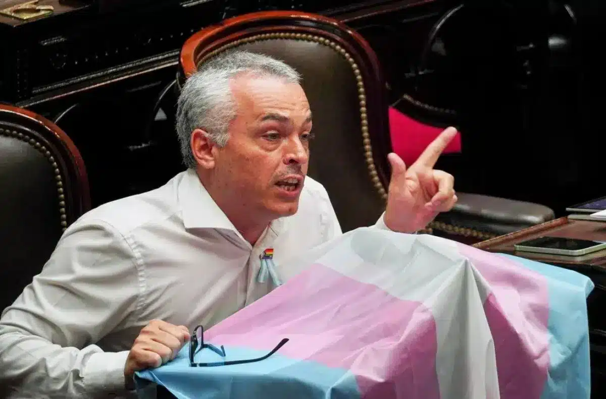Diputado hablando en recinto con bandera diversidad