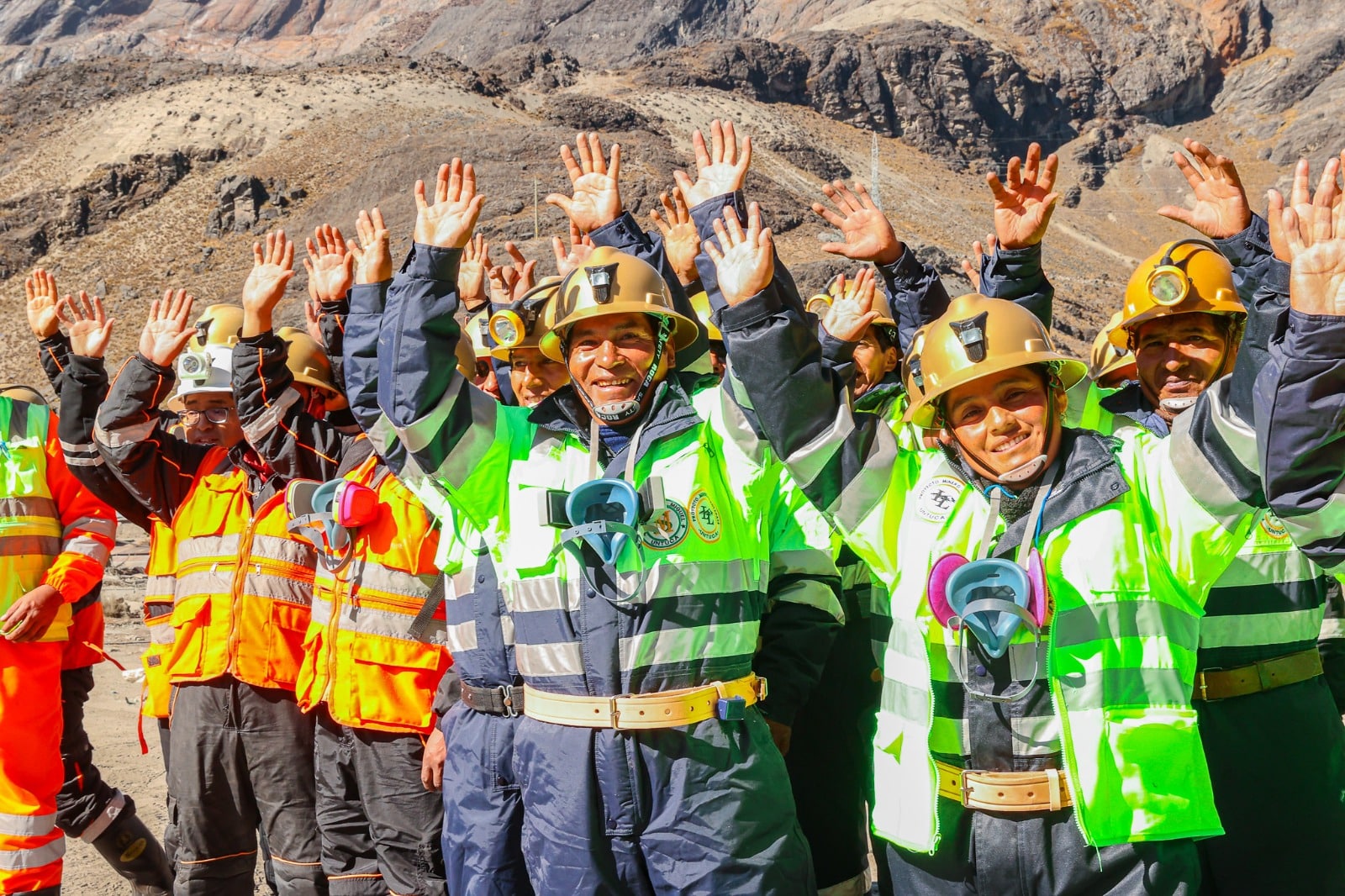 Trabajadores mineros celebrando en entorno monta&ntilde;oso con equipo de seguridad