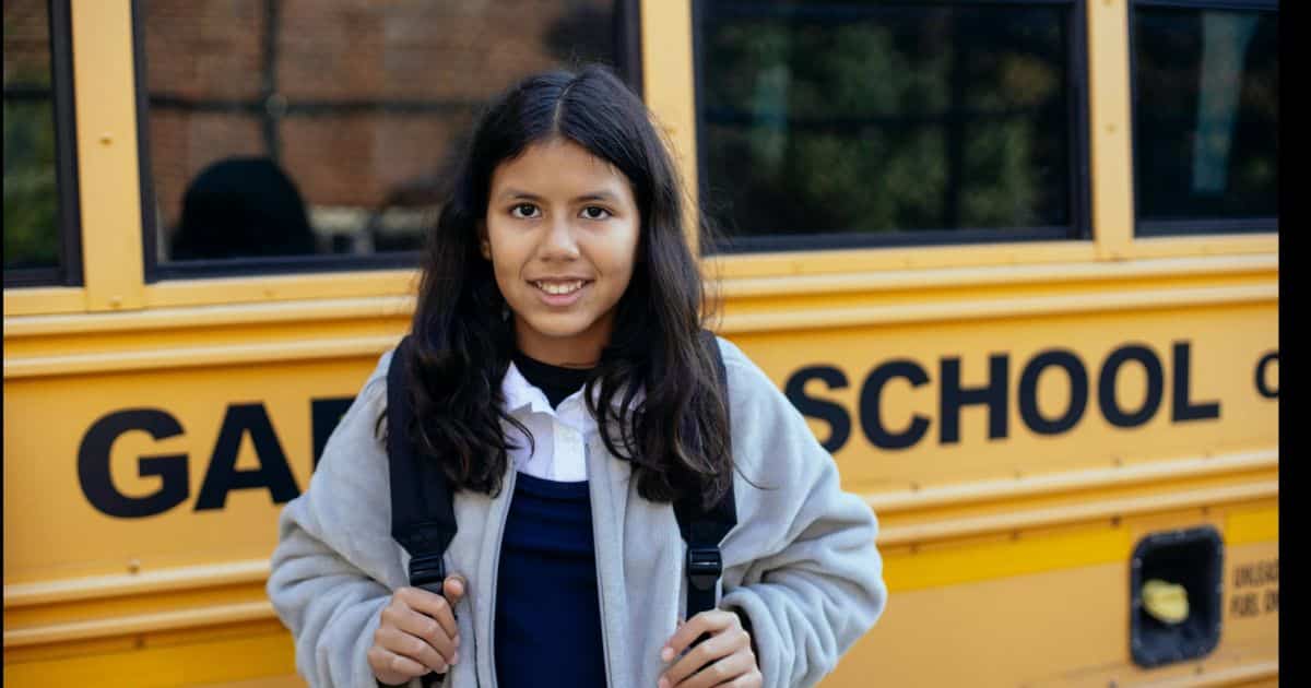 Estudiante frente a autob&uacute;s escolar