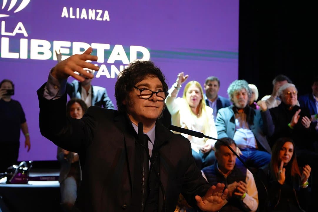 Javier Milei discursando en evento pol&iacute;tico con fondo de ALIANZA LIBERTAD
