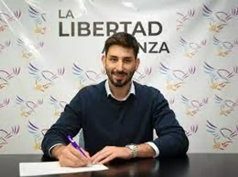 Candidato pol&iacute;tico en evento formal con logotipo de La Libertad Avanza