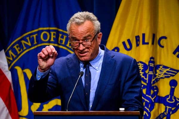 Individuo en podio discutiendo temas de salud con banderas de EE.UU. y salud p&uacute;blica