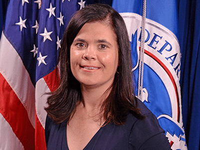 Funcionaria de FEMA en entorno gubernamental con banderas de EE.UU. y Departamento de Seguridad Nacional