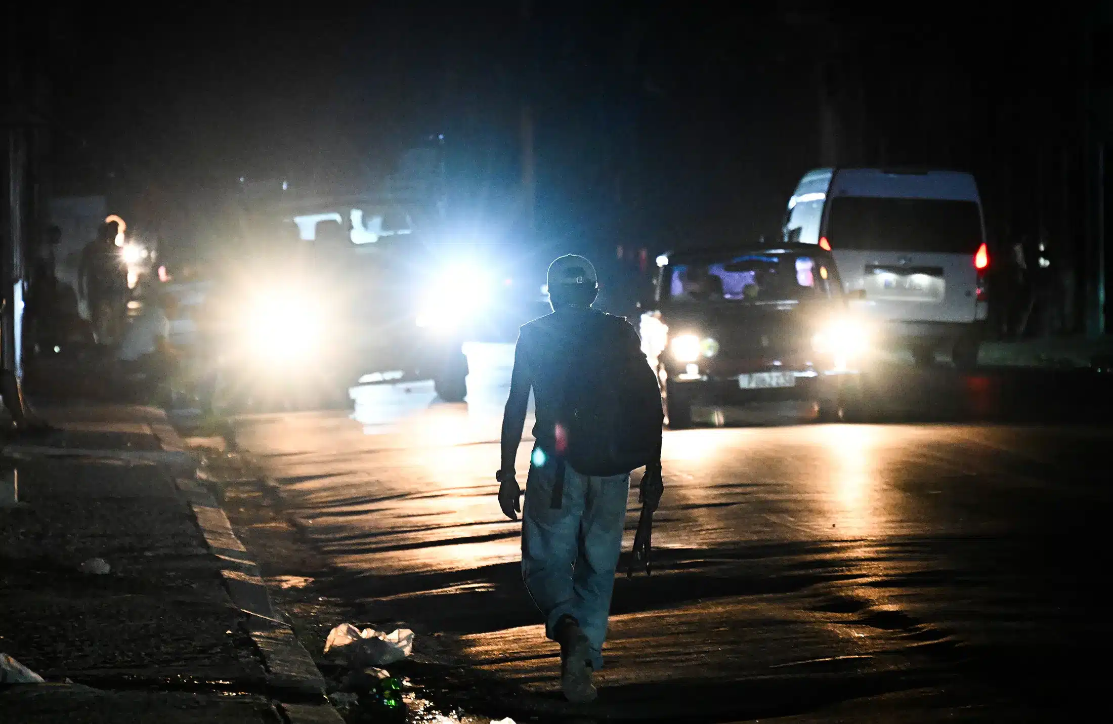 Calle oscura con vehículos iluminados, reflejando crisis energética