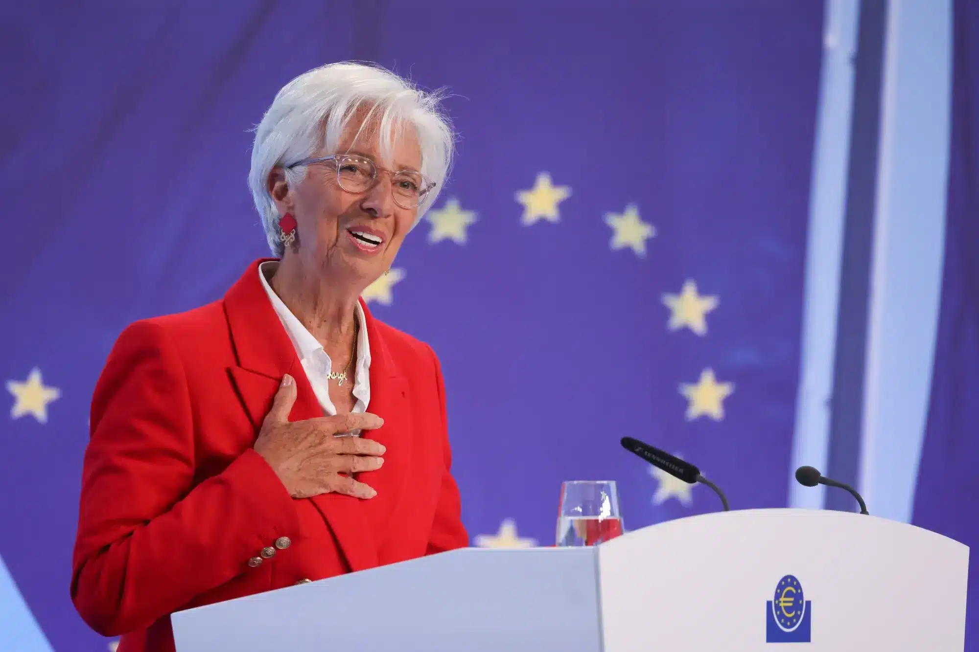 Mujer con blazer rojo y bandera de la UE en evento econ&oacute;mico