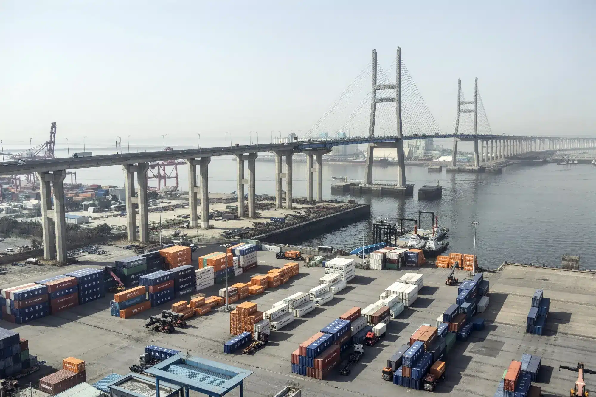 Puerto marítimo con contenedores de carga y grúas, representando el comercio internacional