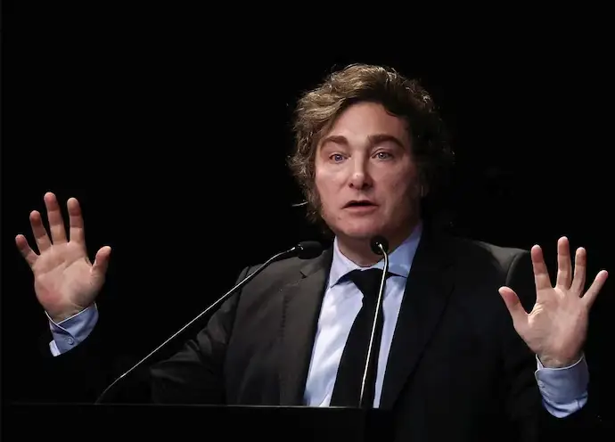 Javier Milei en un evento o conferencia, gesticulando con seriedad