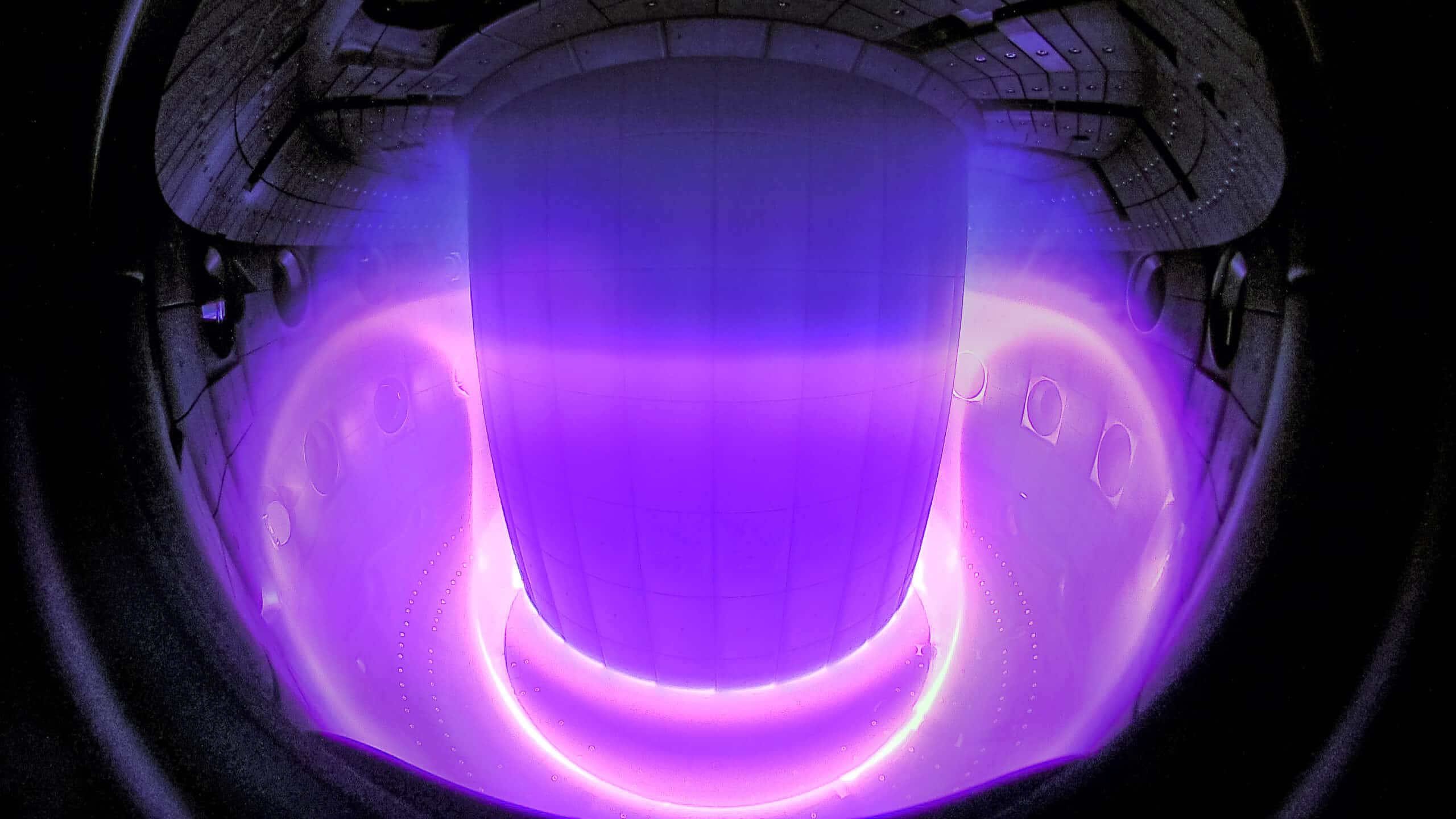Interior de un reactor de fusión con plasma iluminado en tonos púrpuras y azules