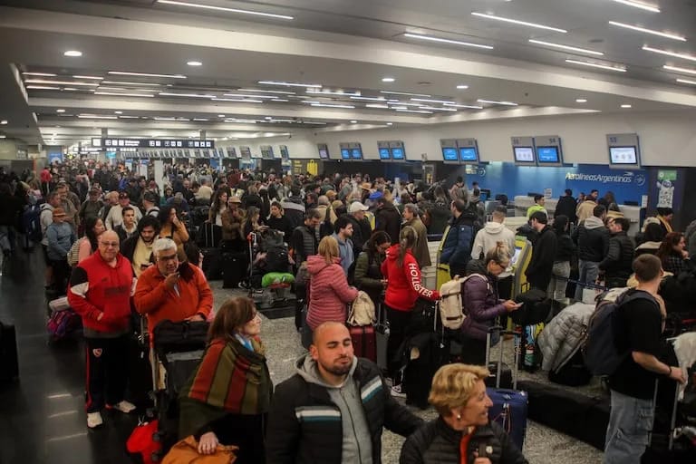 Área de check-in congestionada en aeropuerto con pasajeros y equipaje
