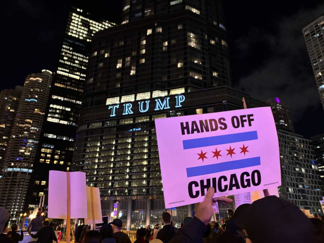 Protesta nocturna frente a edificio Trump con cartel Hands Off Chicago