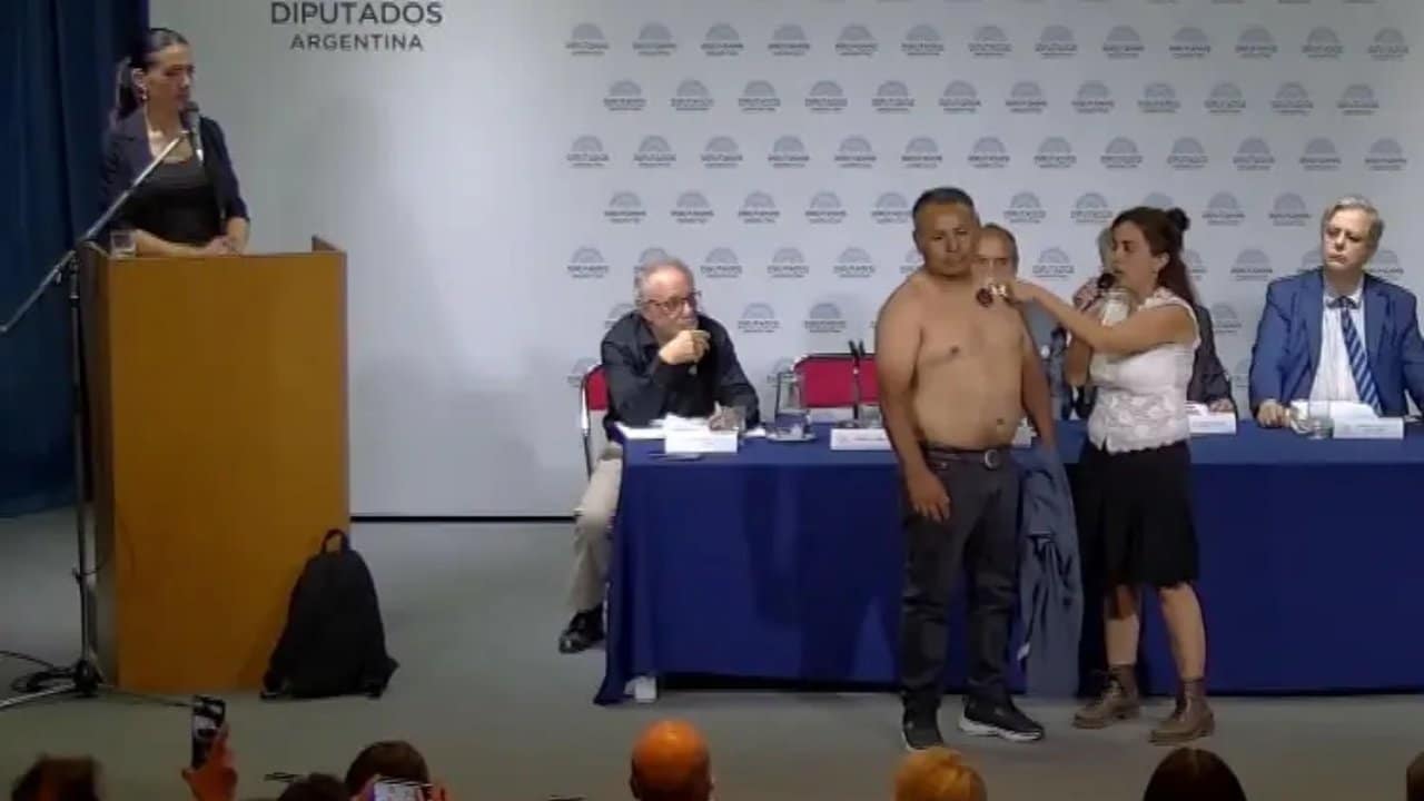 Evento en el Anexo de la Cámara de Diputados con hombre sin camisa y panelistas