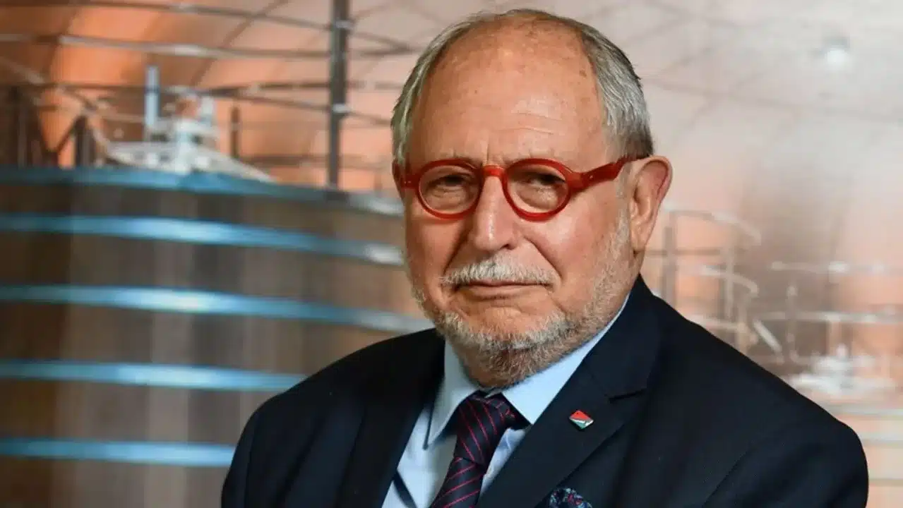 Diego Guelar con gafas rojas en fondo formal