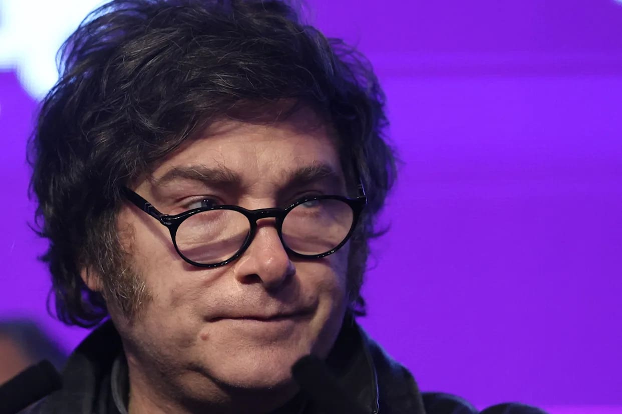 Figura política con cabello rizado y gafas en contexto serio