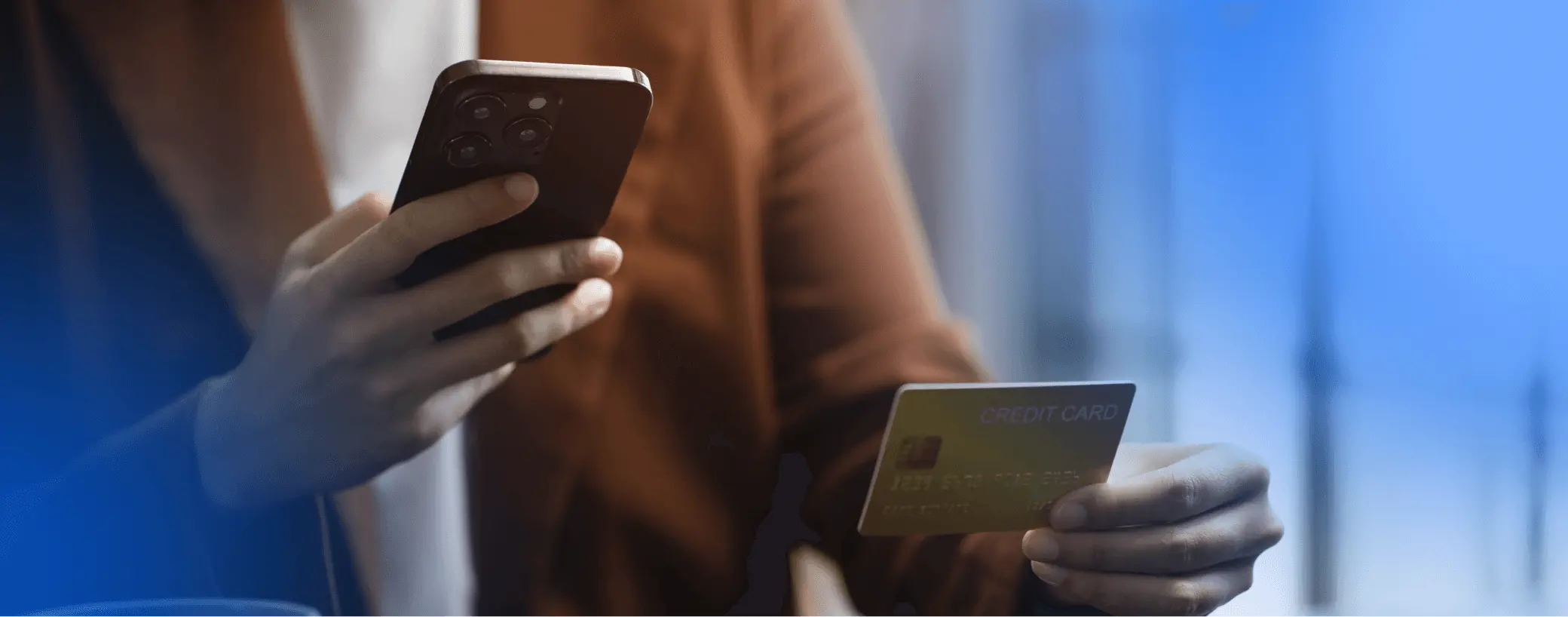 Persona sosteniendo teléfono y tarjeta de crédito en contexto de transacciones digitales