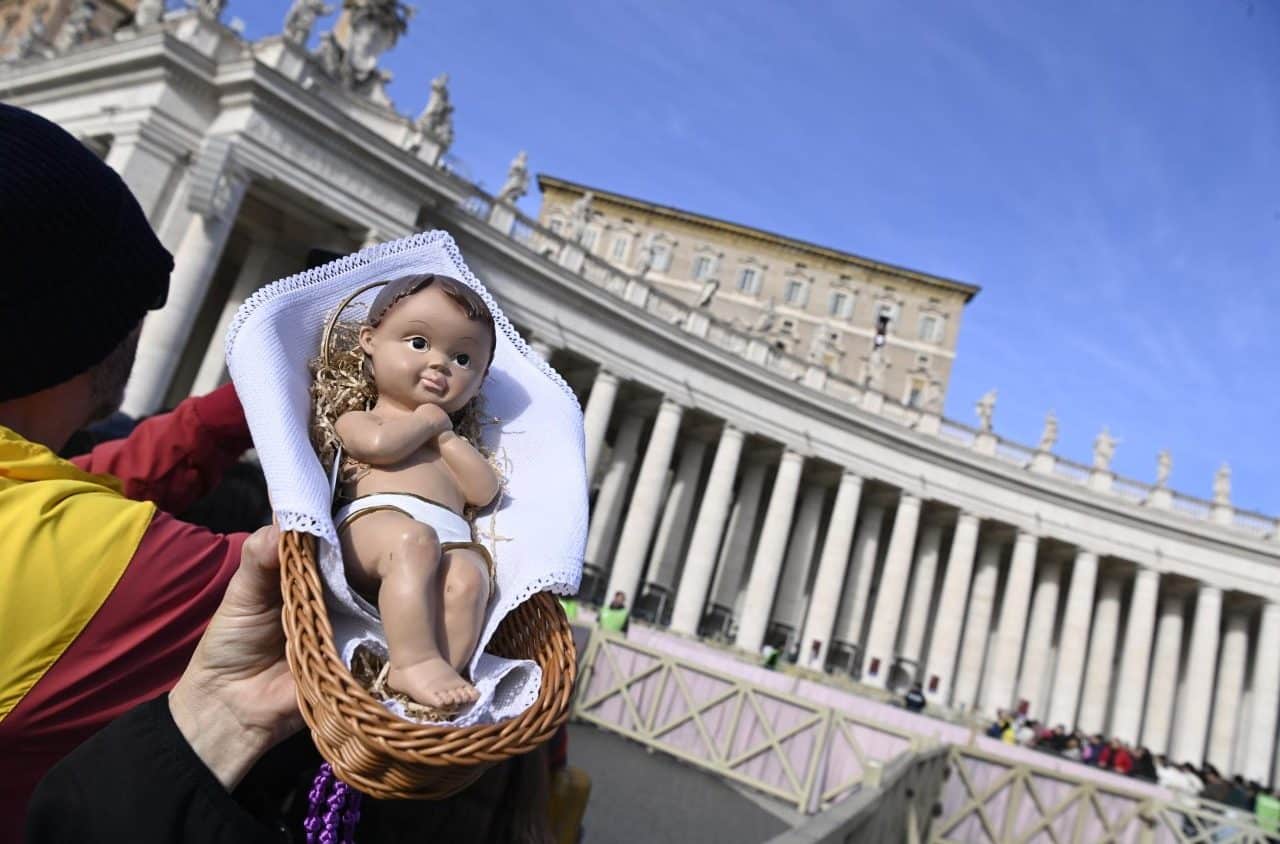 Persona sosteniendo una figura del Ni&ntilde;o Jes&uacute;s en una canasta, con columnas al fondo