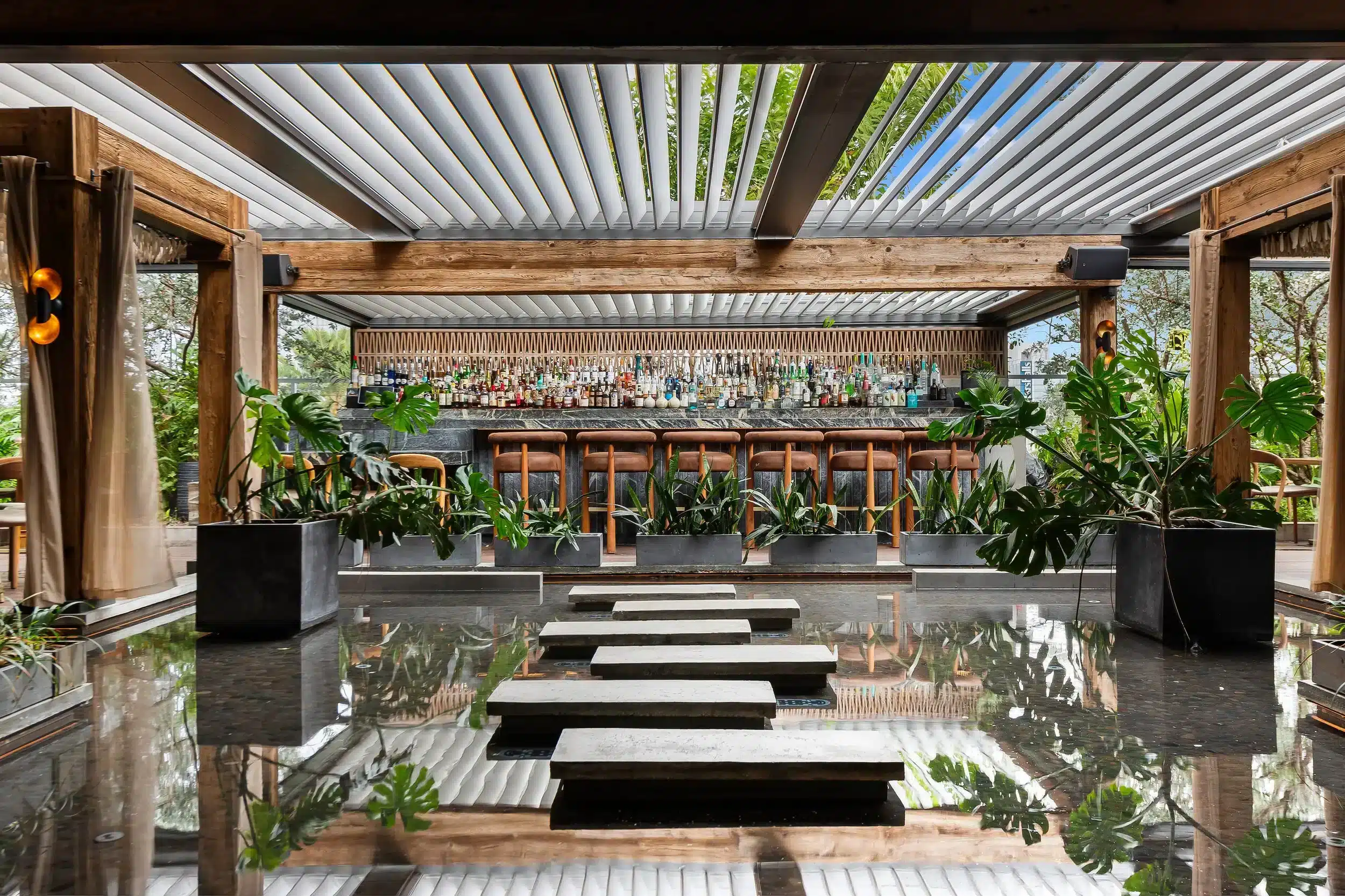 Interior elegante y moderno del restaurante Mila en Miami Beach, con bar y decoraci&oacute;n con madera y plantas