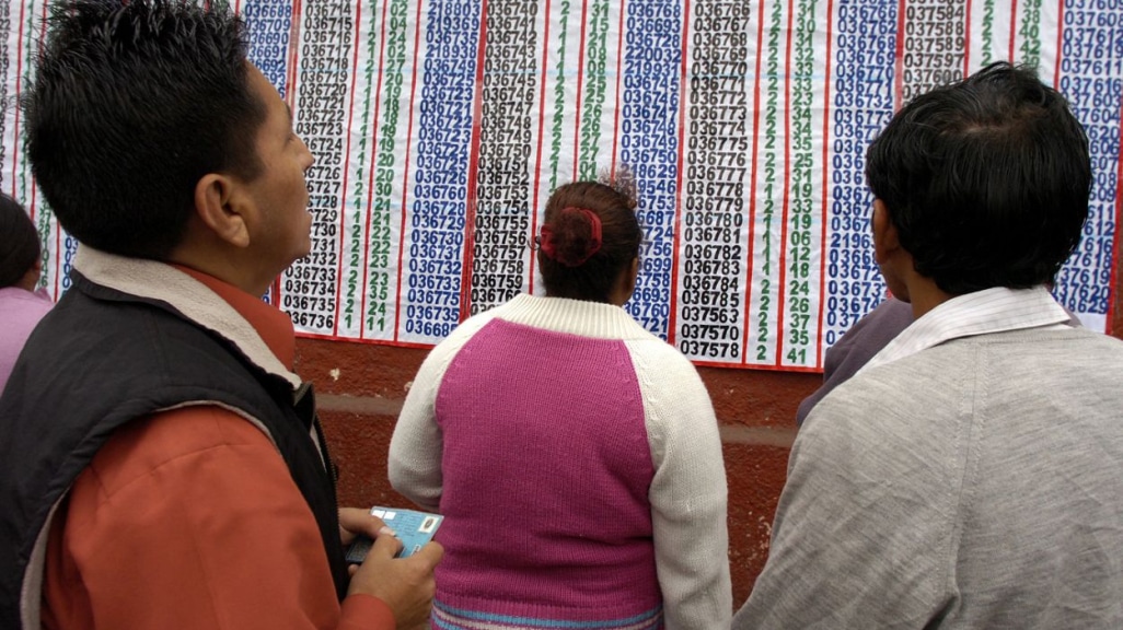 Ciudadanos peruanos consultando el padrón electoral en un panel informativo