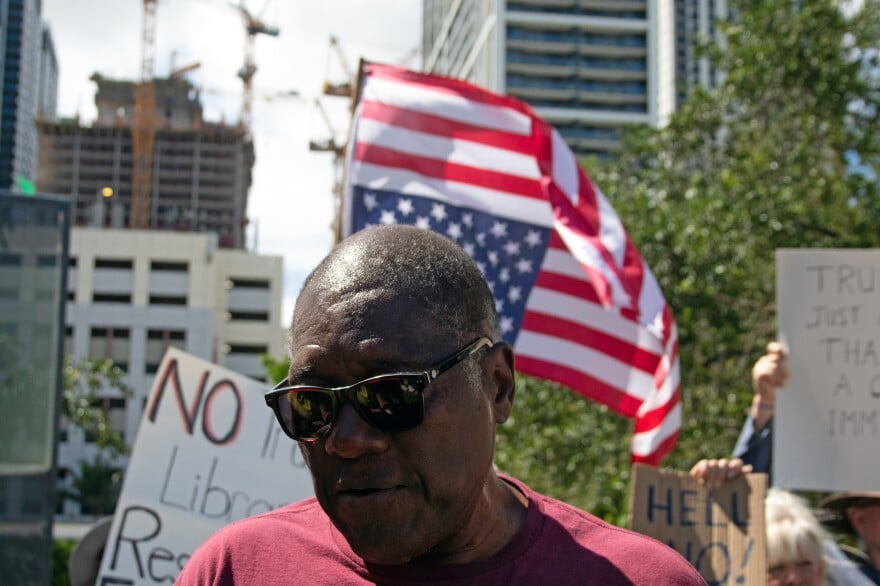 Persona protestando con bandera estadounidense de fondo
