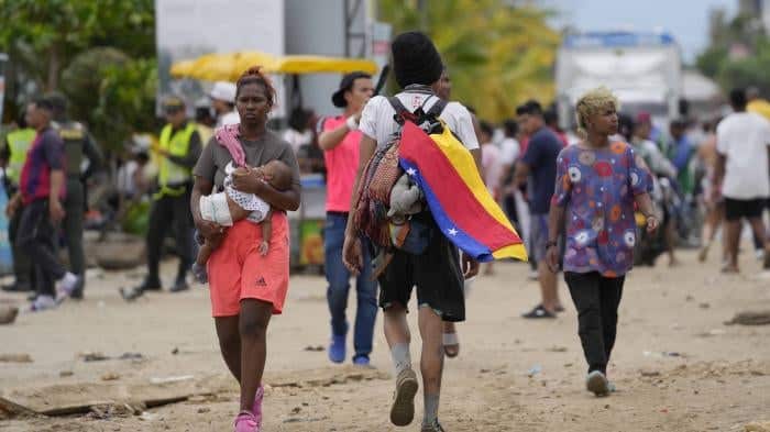 Migrantes venezolanos en tr&aacute;nsito, con bandera de Venezuela