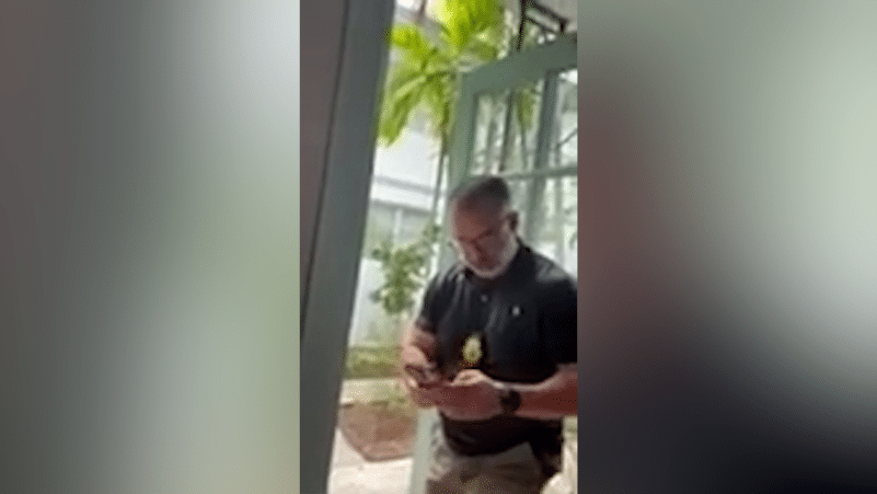 Oficial de polic&iacute;a de pie en la entrada de una casa residencial durante una visita