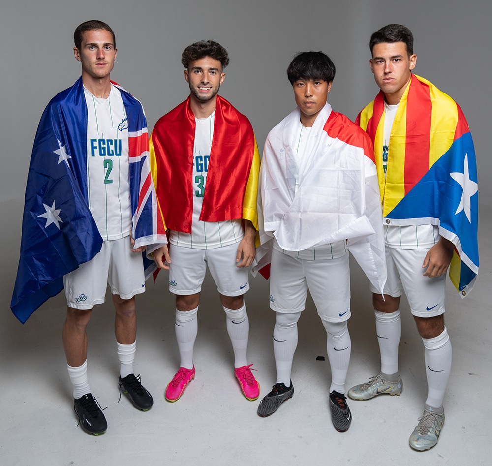 Jugadores de f&uacute;tbol sosteniendo banderas de diferentes pa&iacute;ses, representando diversidad internacional