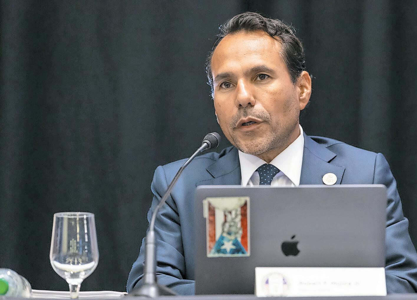 Hombre con traje hablando frente a un micr&oacute;fono, posible representante sindical