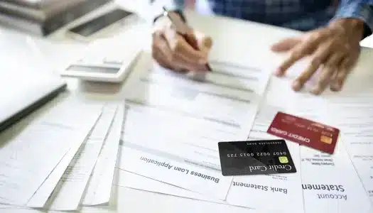 Persona revisando documentos de préstamos y estados de cuenta financieros en una mesa