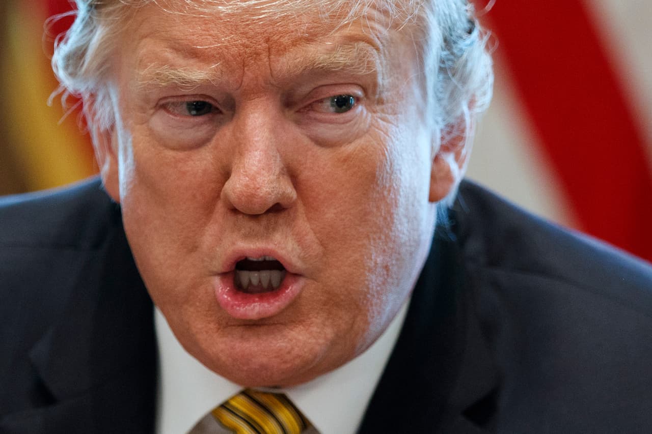 Donald Trump hablando intensamente con banderas de fondo