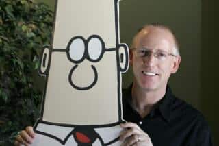Persona sosteniendo un cartel del personaje Dilbert en un entorno de oficina