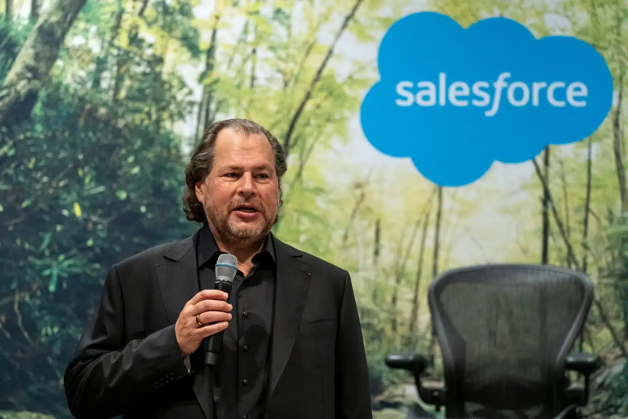 Marc Benioff hablando en un evento de Salesforce con fondo boscoso