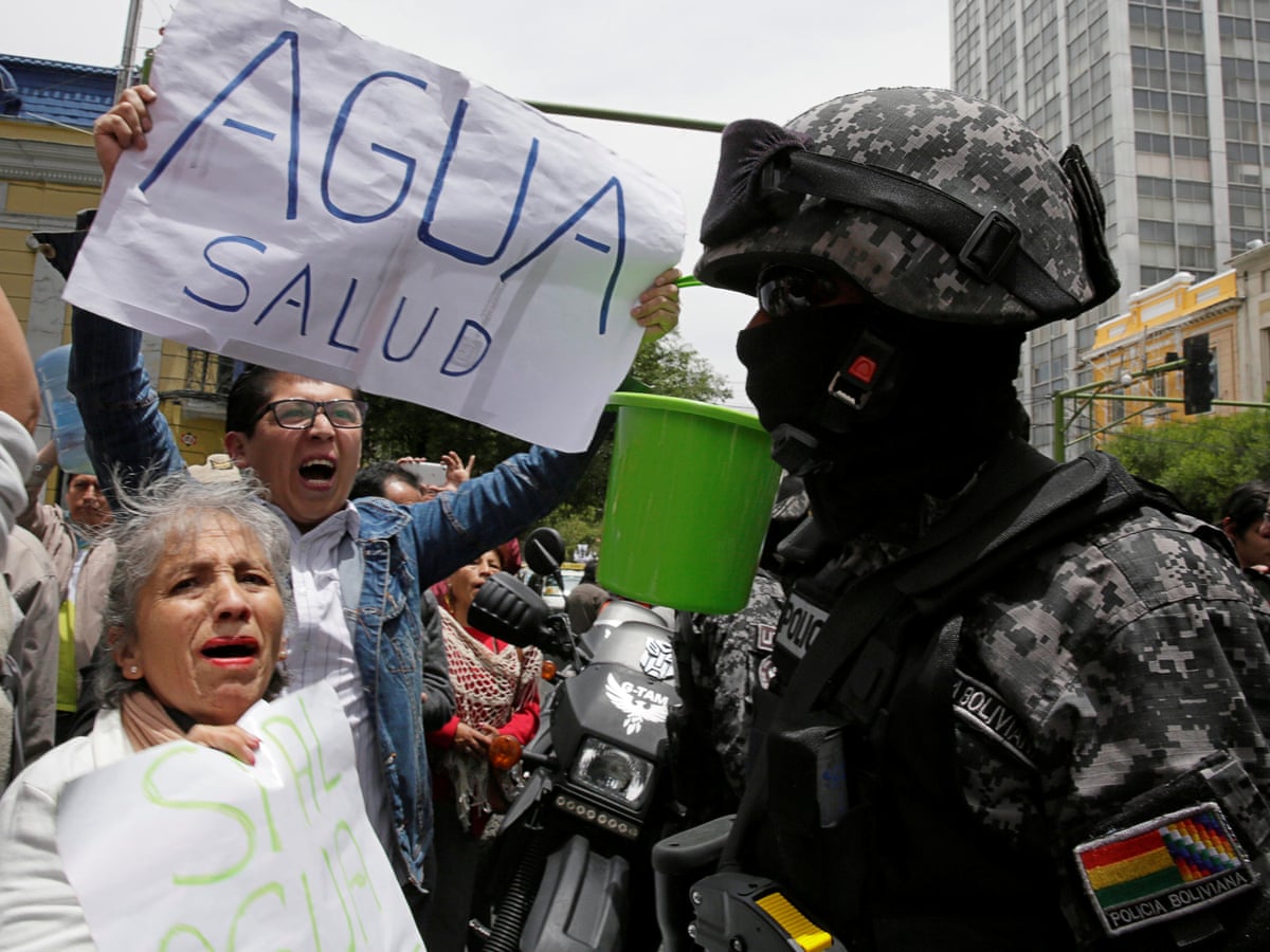 Manifestaci&oacute;n con polic&iacute;a fuertemente armado y personas sosteniendo carteles