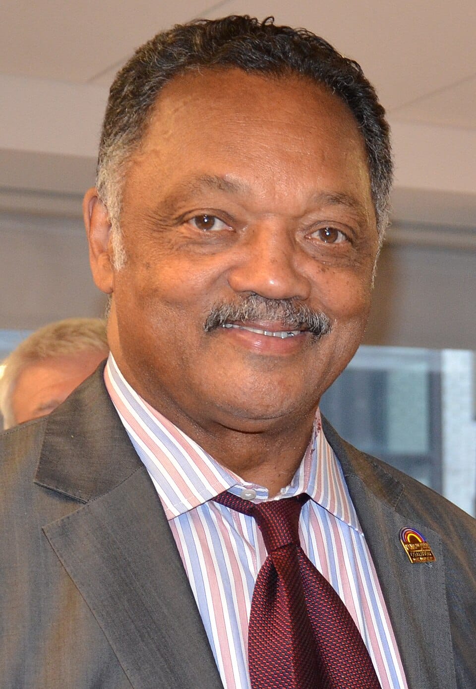 El Reverendo Jesse Jackson sonriendo con traje oscuro y corbata