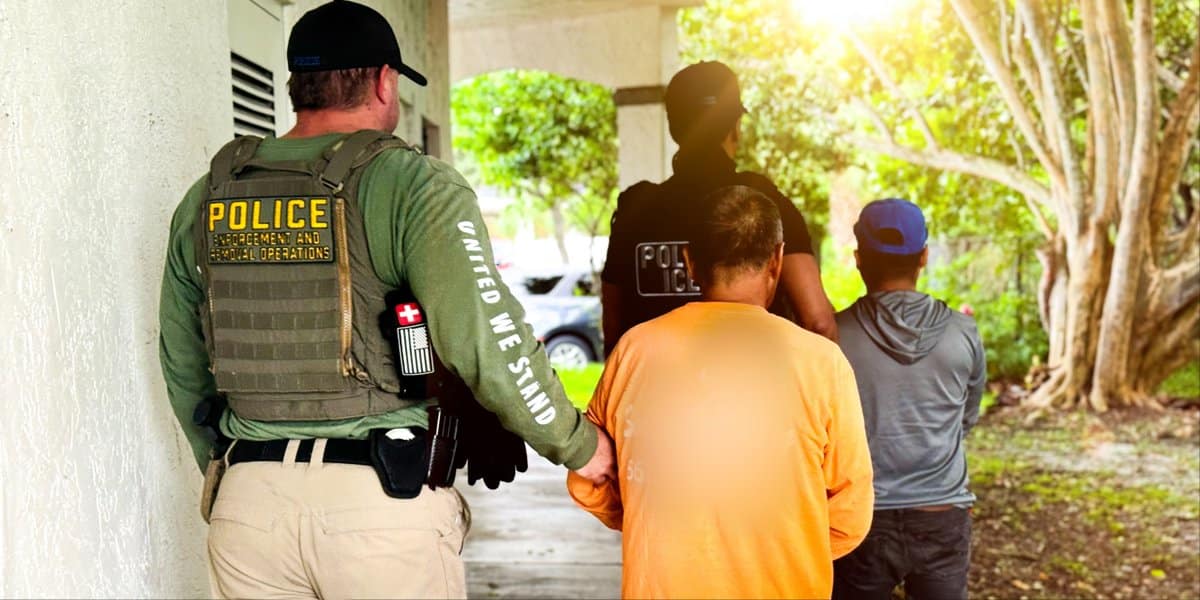 Individuos bajo custodia caminando con un oficial de policía en un entorno residencial