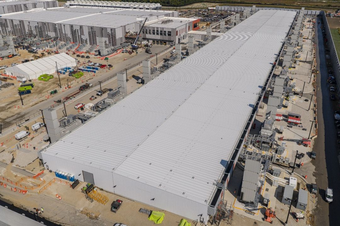 Vasta instalación de un centro de datos en construcción, mostrando edificios metálicos y maquinaria, relevante para la expansión de infraestructura de IA