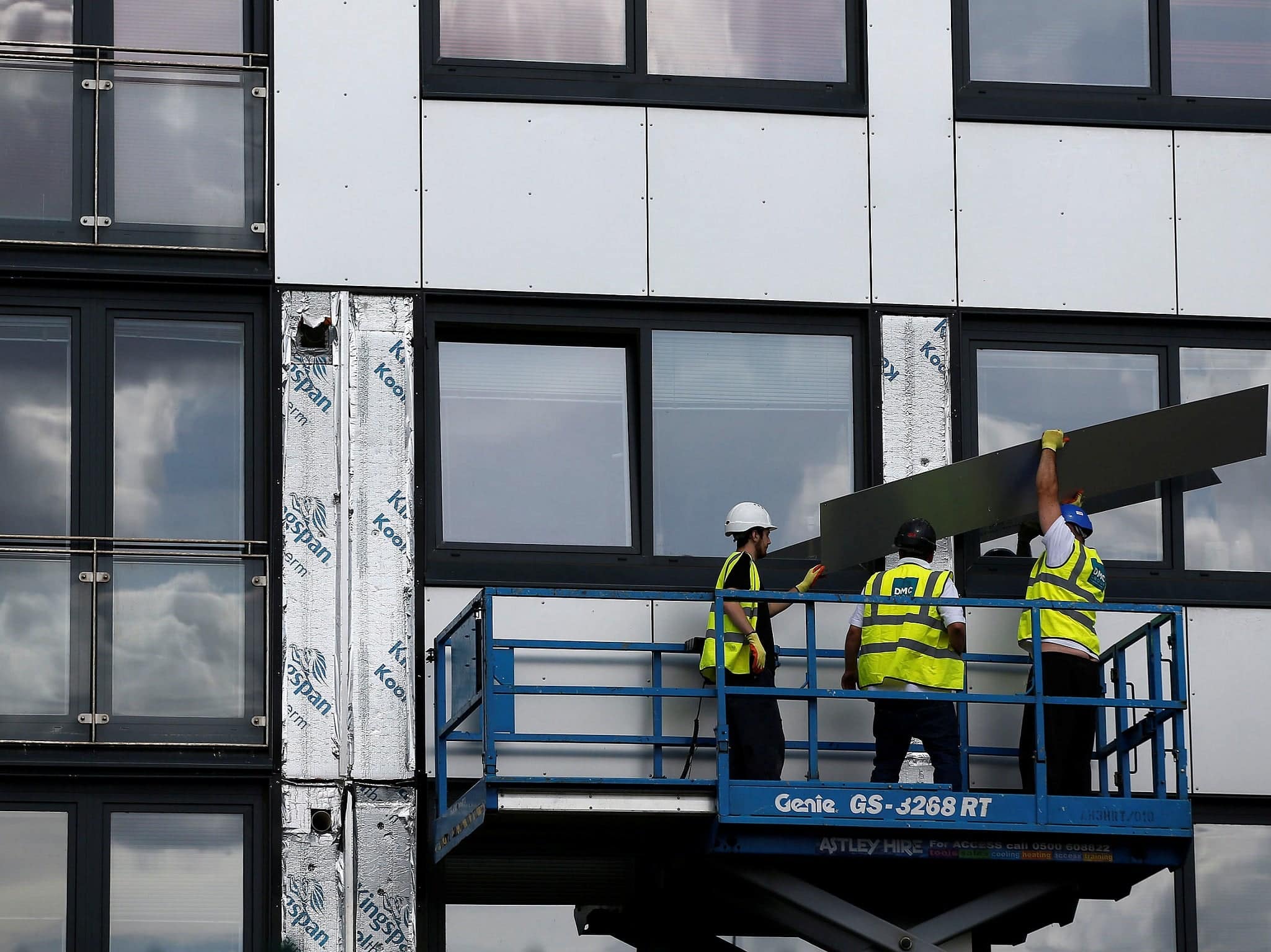 Trabajadores en andamio durante construcción de un edificio, ilustrando proyectos de infraestructura