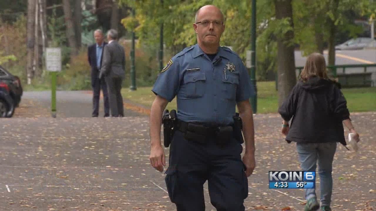 Oficial de policía armado patrullando un sendero en un campus