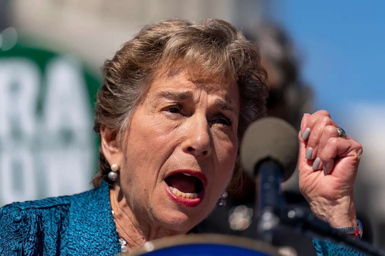 Mujer hablando con pasión en evento político con señal AIPAC de fondo