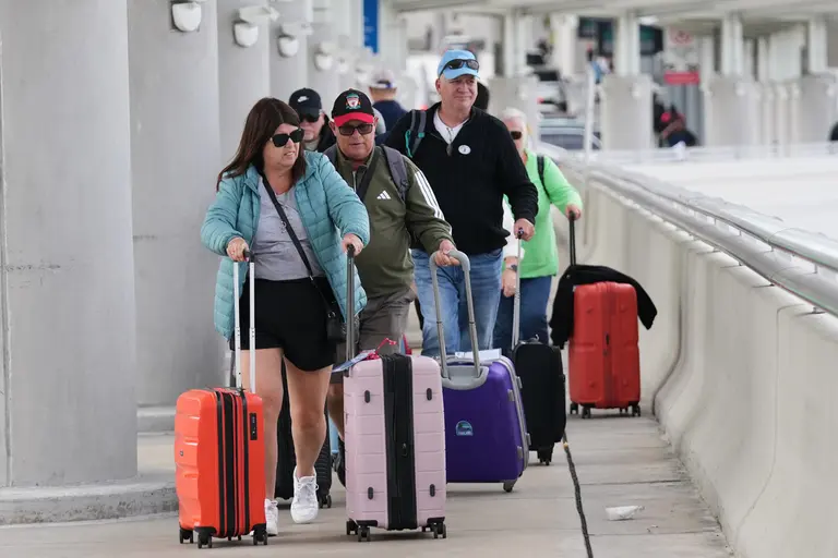 Viajeros con maletas en un aeropuerto, algunos con abrigos