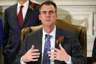 El gobernador de Oklahoma, Kevin Stitt, hablando en un evento formal con traje y corbata