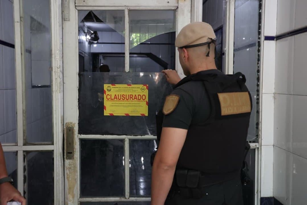 Agente de seguridad revisa cartel de clausura en edificio ocupado