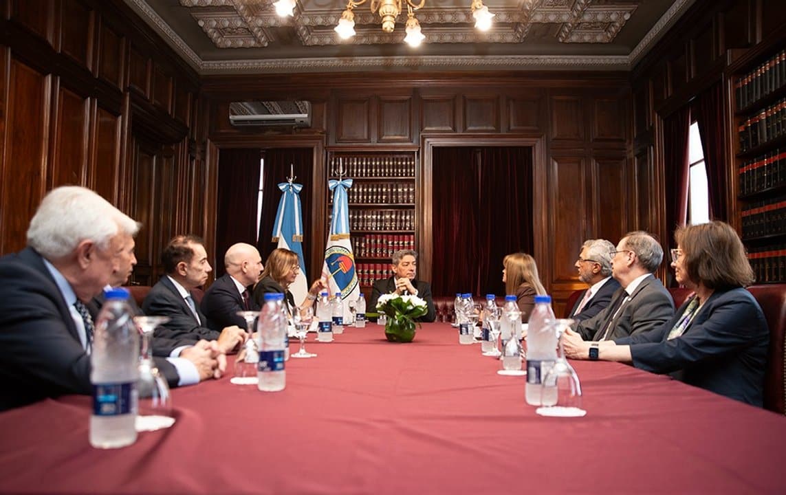 Reuni&oacute;n formal en el Palacio de Justicia con Horacio Rosatti y autoridades de JUFEJUS, con banderas argentinas y una mesa rectangular cubierta con mantel rojo