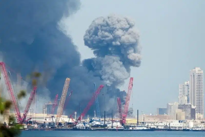Nube de humo en área industrial del Golfo con grúas y barcos