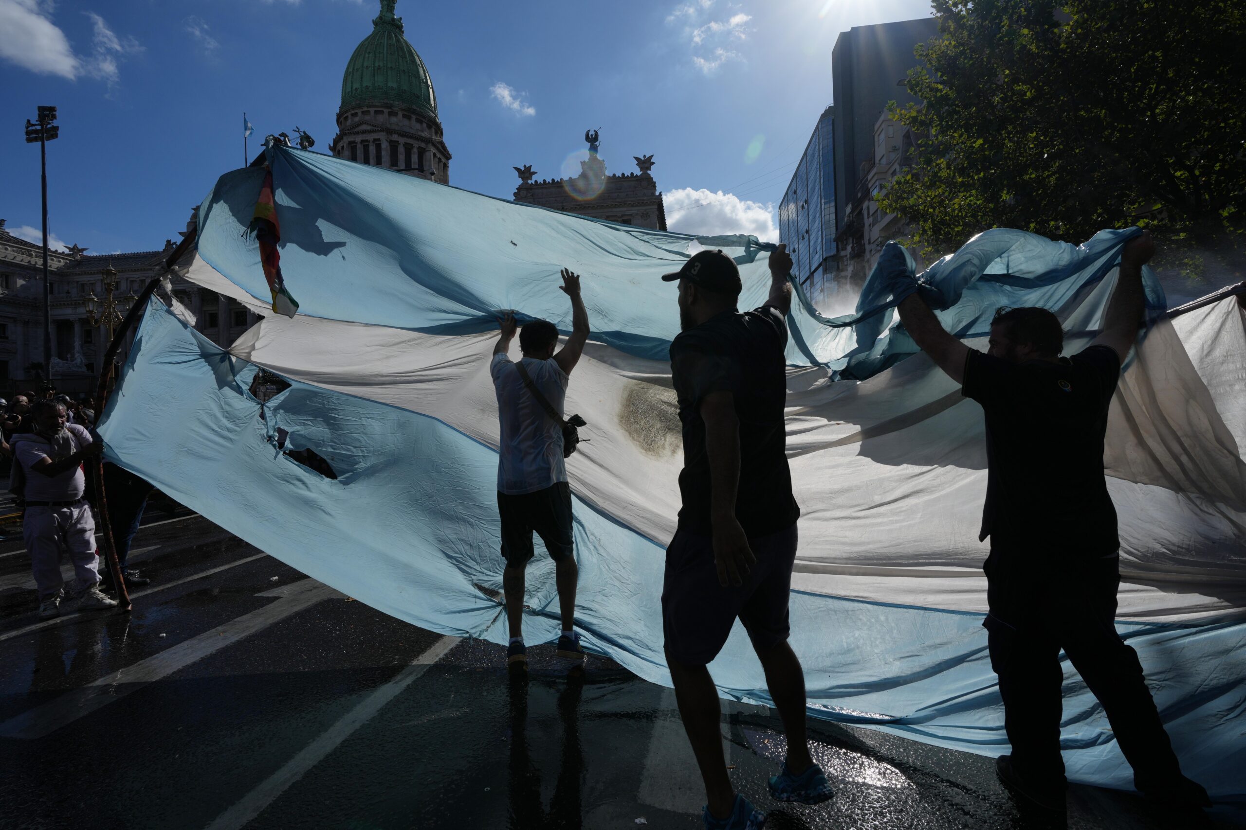 Manifestantes sosteniendo una bandera argentina frente al Congreso