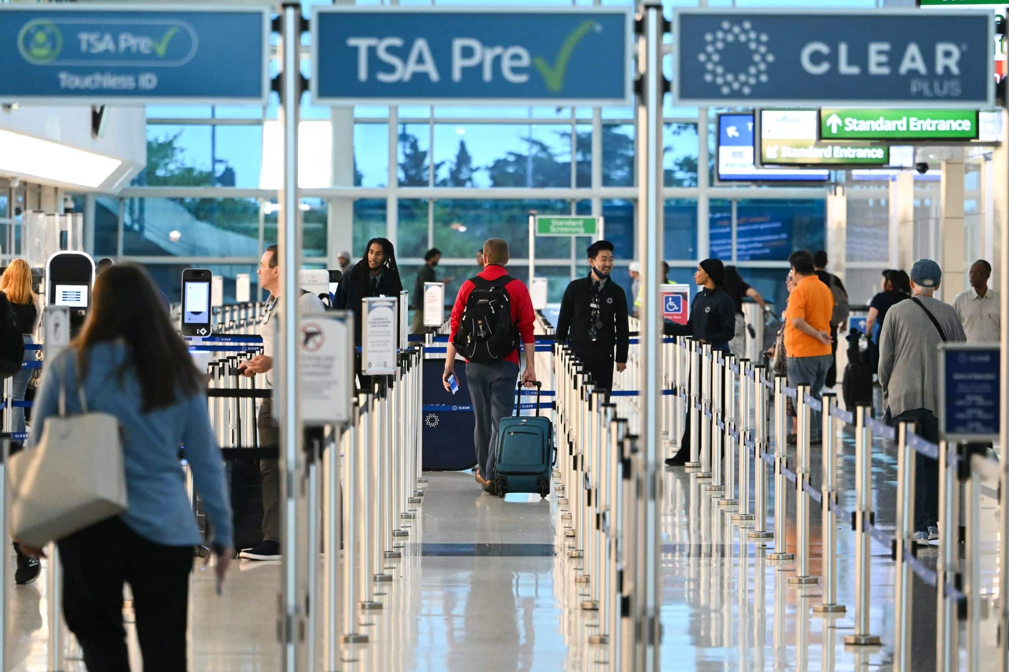 &Aacute;rea de control de seguridad en un aeropuerto con pasajeros en fila y se&ntilde;ales de TSA Pre✓ y CLEAR
