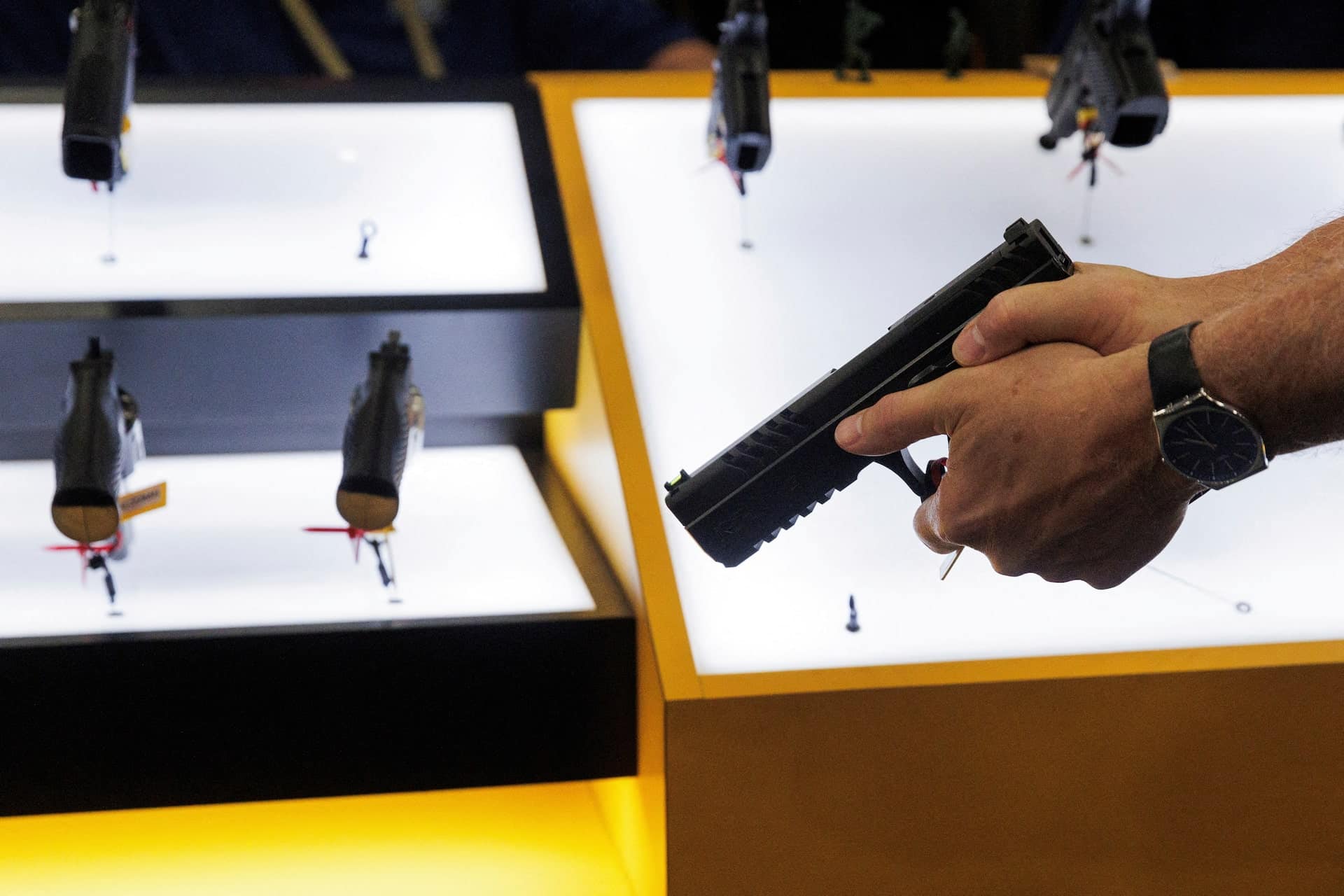 Primer plano de una mano sosteniendo una pistola en una exhibición de armas