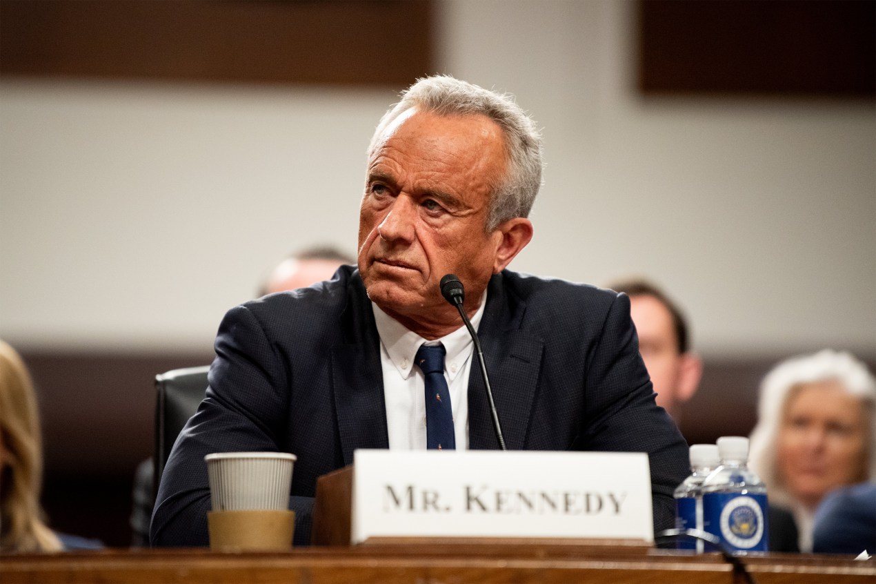 RFK Jr. sentado en una audiencia con cartel 'Mr. Kennedy'