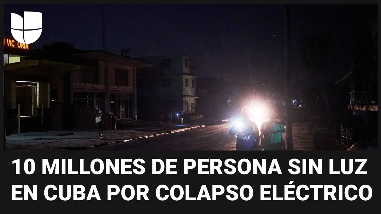 Escena urbana oscura en Cuba durante el apagón, con dos personas usando una linterna para iluminar el camino