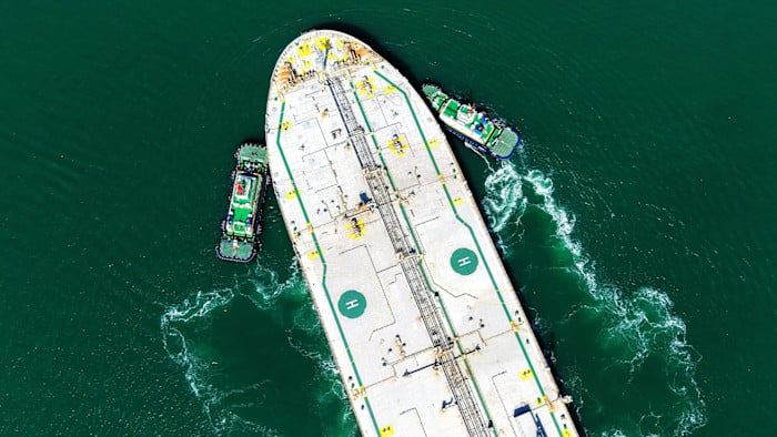 Barco petrolero con remolcadores navegando en aguas verdes