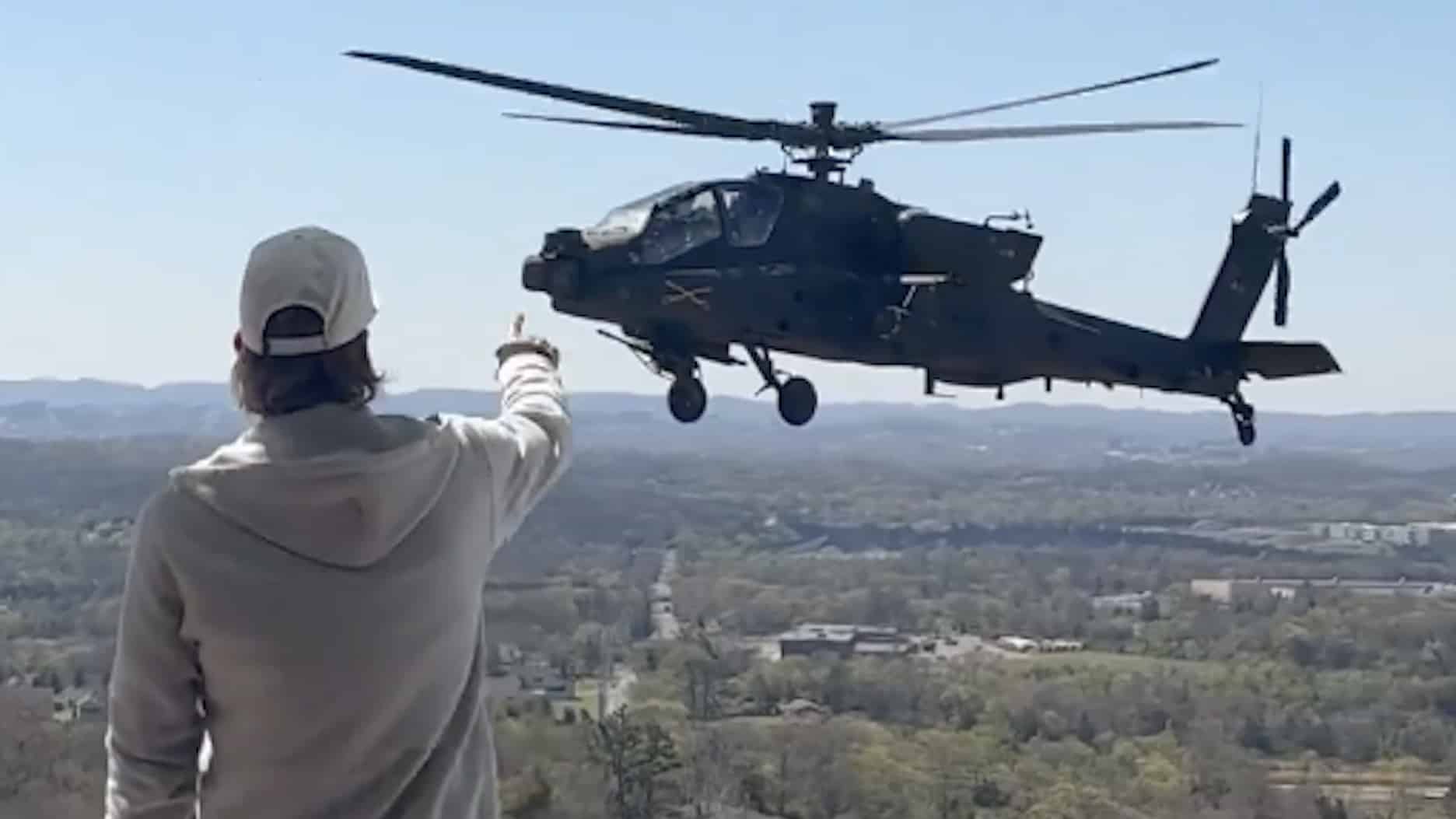 Helic&oacute;ptero Apache volando cerca de una persona, en un paisaje monta&ntilde;oso