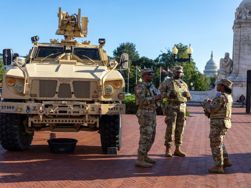 Veh&iacute;culo militar MATV y soldados conversando en plaza p&uacute;blica